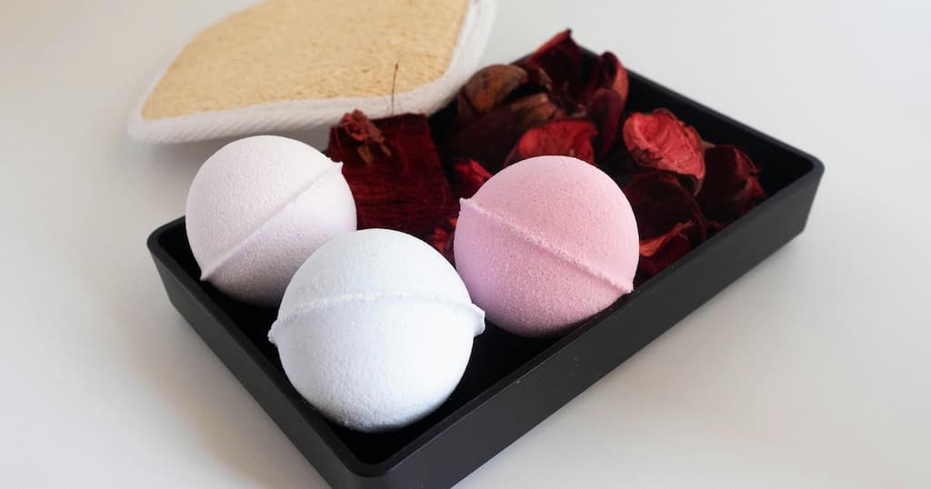 Close-up of pastel bath bombs with a loofah and dried petals, creating a relaxing spa-like vibe