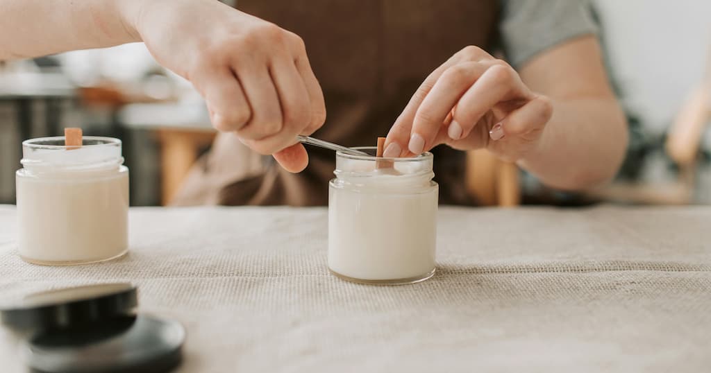 Close-up of artisan making handmade candles with wooden wicks in a cozy workshop setting