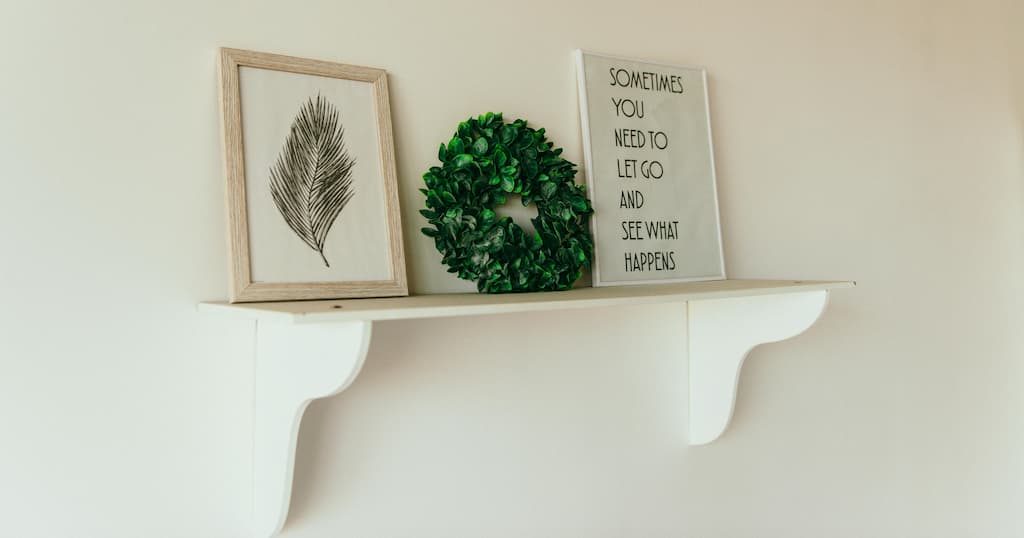Minimalist shelf featuring framed art, a green wreath, and a motivational quote display