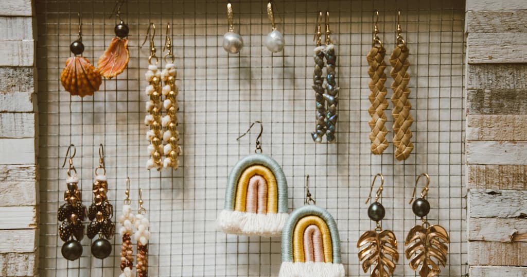 Handmade earrings neatly arranged in a rustic wooden frame with a grid-style display backdrop