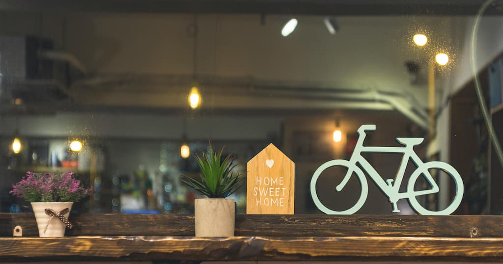 Cozy indoor space with greenery, a wooden bicycle, and 'Home Sweet Home' decorative sign